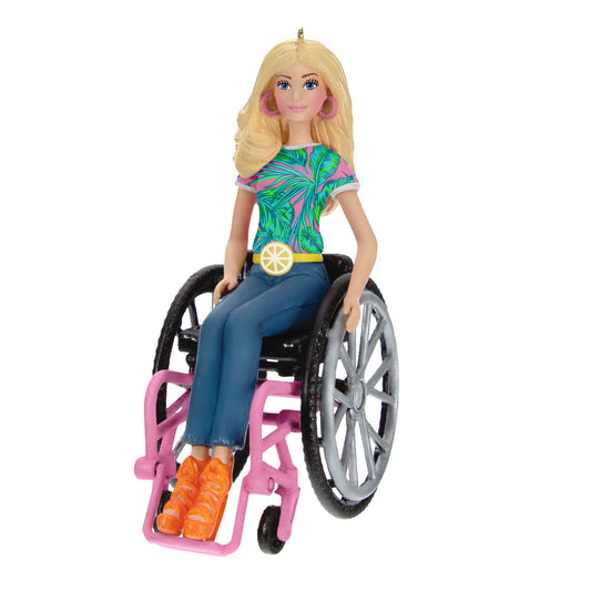 Christmas ornament depicting blonde Barbie wearing jeans, a tropical shirt, orange high heel sandals, pink hoop earrings, and a lemon belt sitting in a pink wheel chair. 