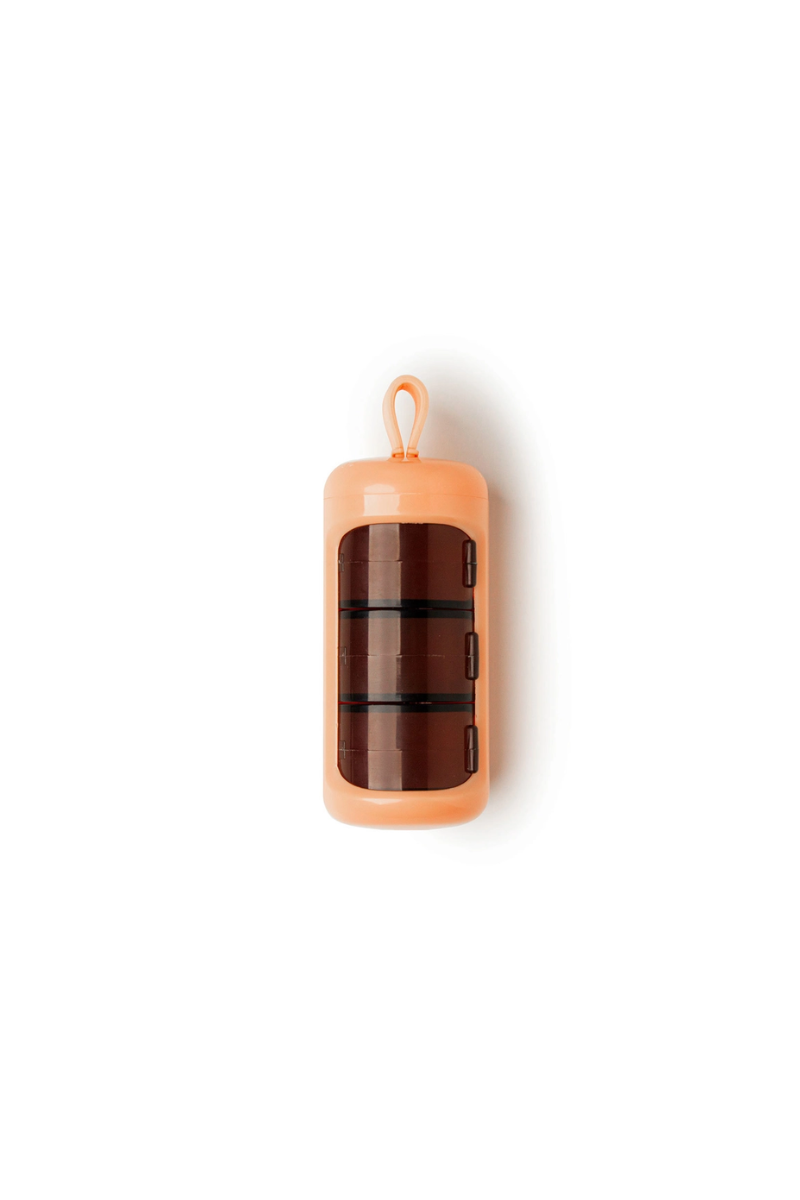 A peach colored cylindrical pill case.