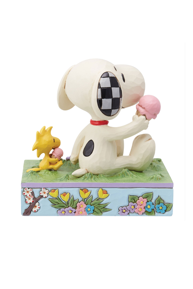 Spring themed figuring of Snoopy and Woodstock siting on the grass eating ice cream. The base of the figurine is sky blue with floral embellishments.