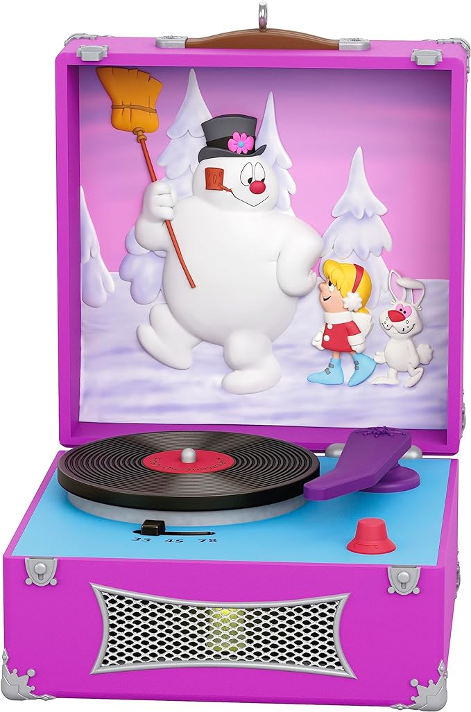 A Christmas ornament of a fuchsia and turquoise record player with a scene from "Frosty the Snowman" depicted on the inside of the lid. 