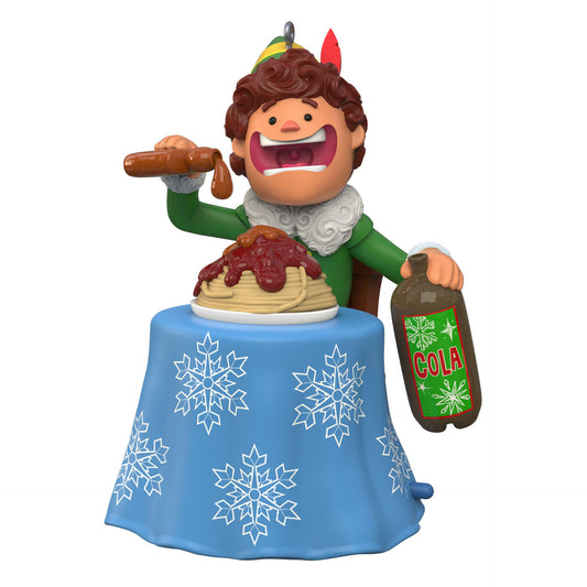 A Christmas ornament depicting Buddy the Elf from the movie "Elf" pouring maple syrup over spaghetti and holding a cola, sitting at a table with a blue and white snowflake table cloth.