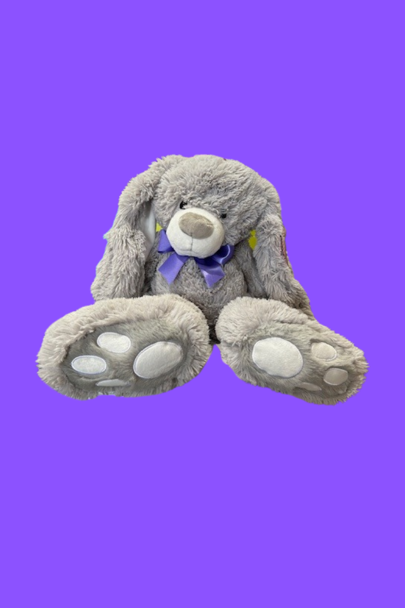 A grey bunny plush with a purple ribbon around its neck.
