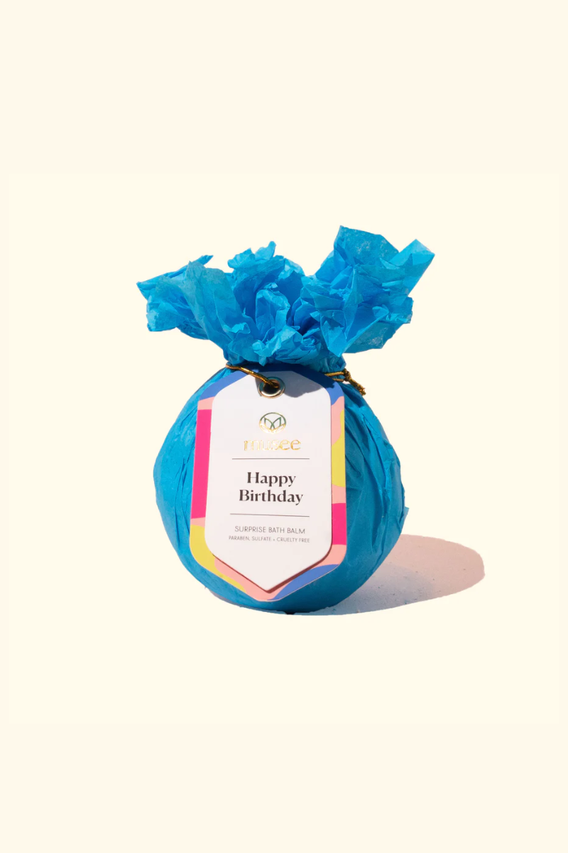 Musee bath bomb wrapped in teal tissue paper. 