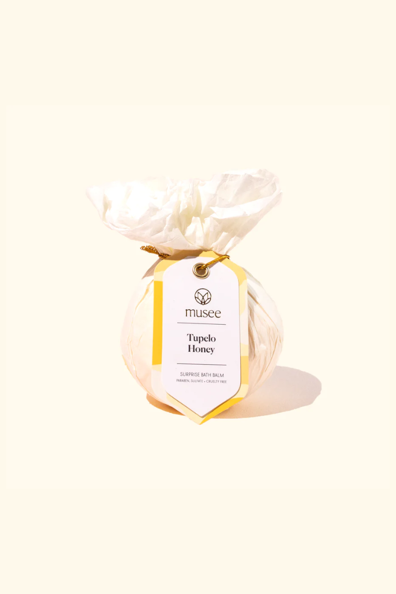 Musee bath bomb wrapped in light pink tissue paper.