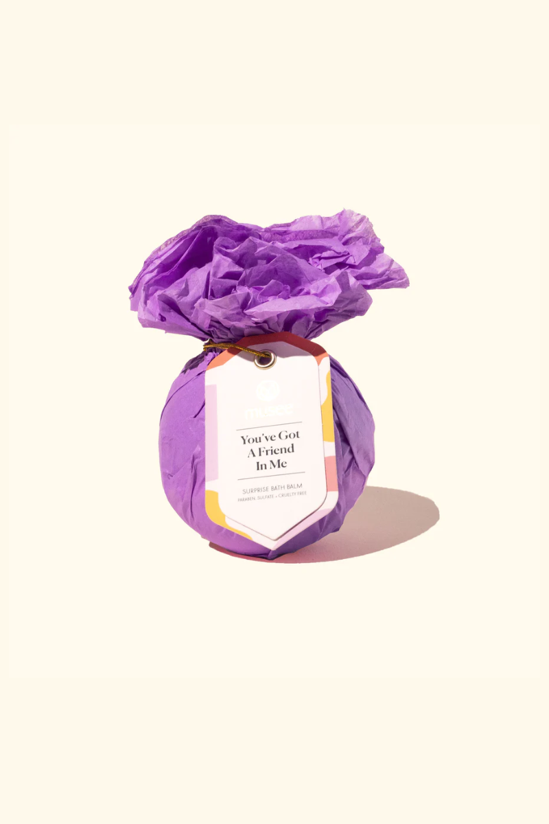 Musee bath bomb wrapped in purple tissue paper. 