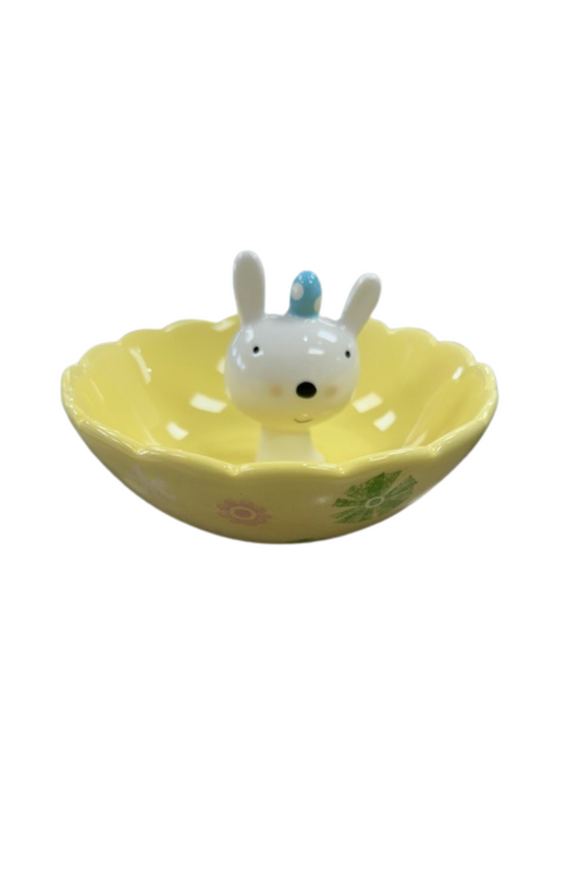 Yellow jewelry dish with Easter designs and a bunny head coming up out of the center with a blue Easter egg on its head.
