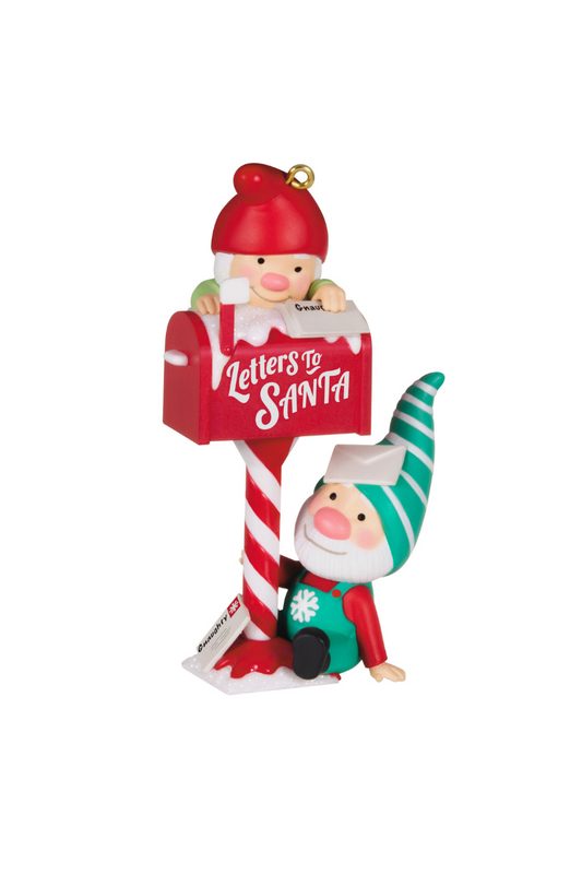 A Christmas ornament of a red mailbox with on a candy striped pole with the words "Letters to Santa" in white on the side of the mailbox. One elf wearing green is sitting below the mailbox and one elf wearing red is climbing on top of the mailbox.
