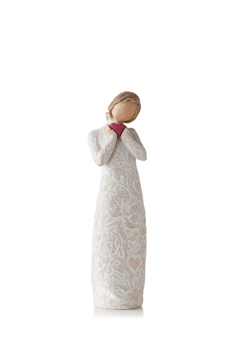 A Willowtree figure of a girl in white with her brown hair pulled back. She is holding a red heart.